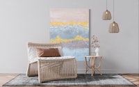 an abstract painting hangs above a chair in a living room