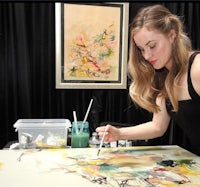 a woman is painting on a canvas in front of a table