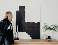 a woman standing in front of a black and white painting