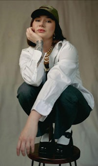a woman sitting on a stool with a hat on her head