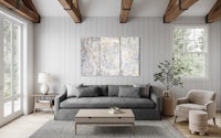 a living room with a grey couch and wooden beams