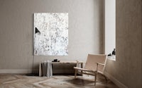 an abstract painting hangs above a chair in a room