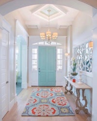 an entryway with a turquoise door and a colorful rug