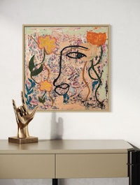 a framed painting of a woman's face on a desk