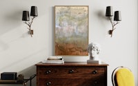 an abstract painting hangs above a dresser in a living room